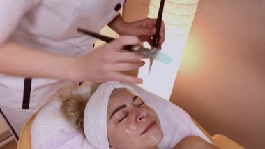 Profesyonel güzellik kadın yüzünde fırçalar ile maske uygulama.