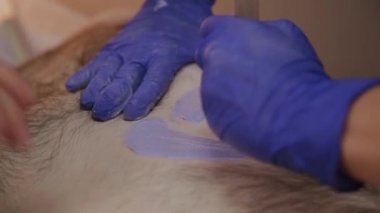 Profesyonel güzellik bir güzellik salonunda bir adam için ağda yapar.