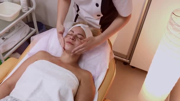 Mujer haciendo masaje facial en el salón de spa . — Vídeo de stock