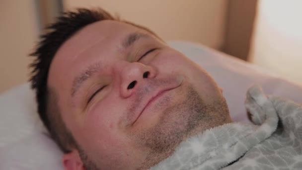 Красивый мужчина лежит на диване у косметолога . — стоковое видео