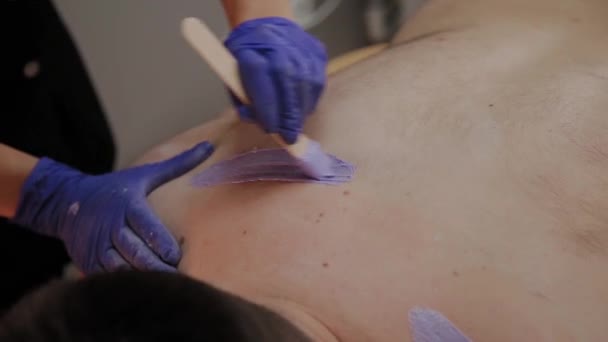 Esteticista profissional faz depilação para um homem em um salão de beleza . — Vídeo de Stock