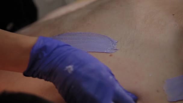 Professionell kosmetolog gör vaxning till en man i en skönhetssalong. — Stockvideo