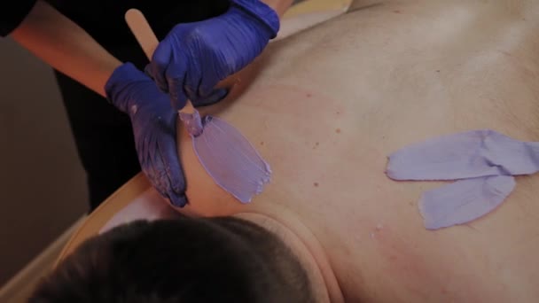 Professional beautician makes waxing to a man in a beauty parlor. — Stock Video