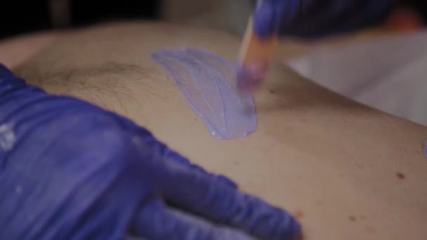 Esteticista profissional faz depilação para um homem em um salão de beleza . — Vídeo de Stock
