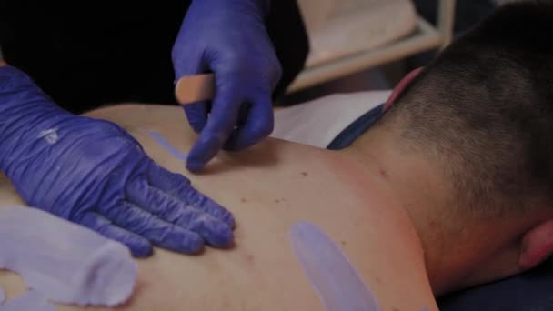 Professionele schoonheidsspecialiste maakt waxen aan een man in een schoonheidssalon. — Stockvideo