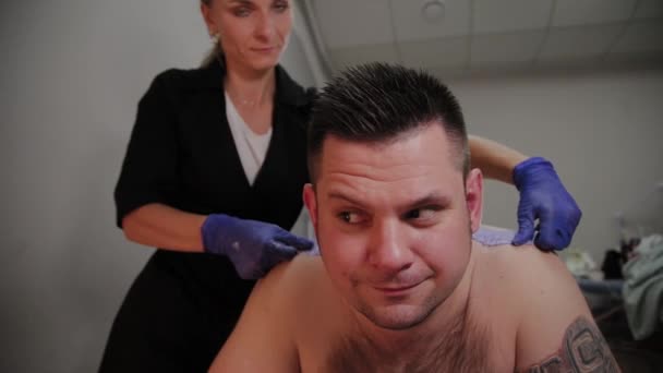 Esteticista profesional hace depilación con cera a un hombre en un salón de belleza . — Vídeos de Stock