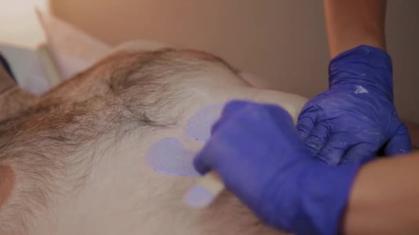 Professionell kosmetolog gör vaxning till en man i en skönhetssalong. — Stockvideo