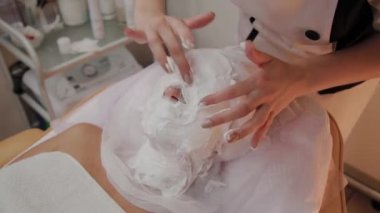 Profesyonel güzellik yüz bir köpük maskesi uygular.