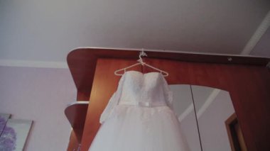 Odada bir askı asılı güzel gelinlik.