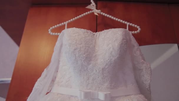 Bellissimo abito da sposa appeso a un appendiabiti nella stanza . — Video Stock