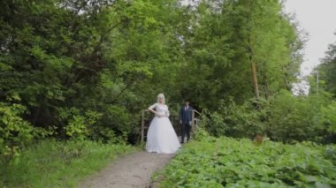 Güzel gelin ve damat ormanda eski bir demir köprü üzerinde. Damat sevgilisini okşur.