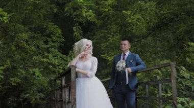 Güzel gelin ve damat ormanda eski bir demir köprü üzerinde. Damat sevgilisini okşur.