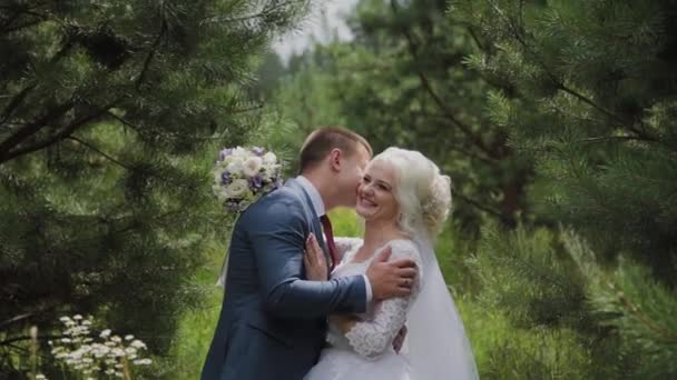 Molto bella sposa e sposo si tengono per mano e si abbracciano nella foresta . — Video Stock