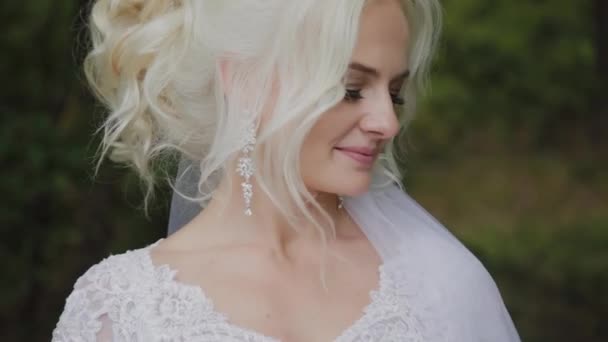 Bella sposa bionda nella foresta si accarezza, raddrizza i capelli . — Video Stock