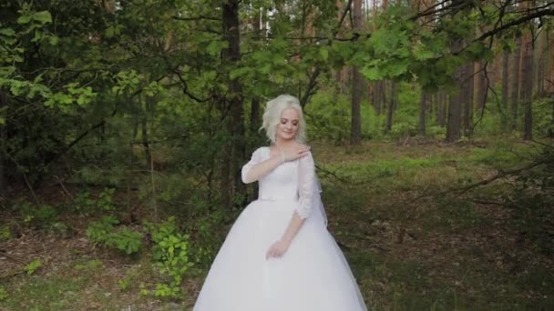 Hermosa novia rubia en el bosque se acaricia, endereza su cabello . — Vídeos de Stock