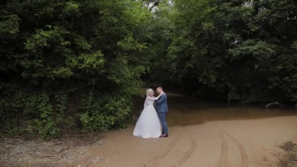 Gyönyörű vőlegény és szőke menyasszony a patak az erdőben. — Stock videók