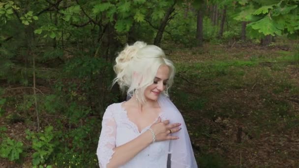 Belle mariée blonde dans la forêt se caresse, redresse ses cheveux . — Video