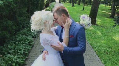 Mutlu yeni evliler parkta el tutarak yürümek, sarılmak öpücük.