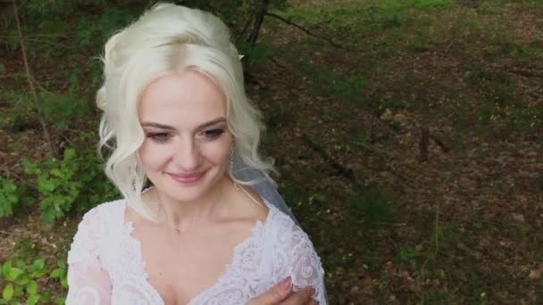 Linda noiva loira na floresta acaricia-se, endireita o cabelo . — Vídeo de Stock