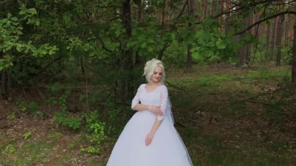 Beautiful blonde bride in the forest strokes herself, straightens her hair. — Stock Video