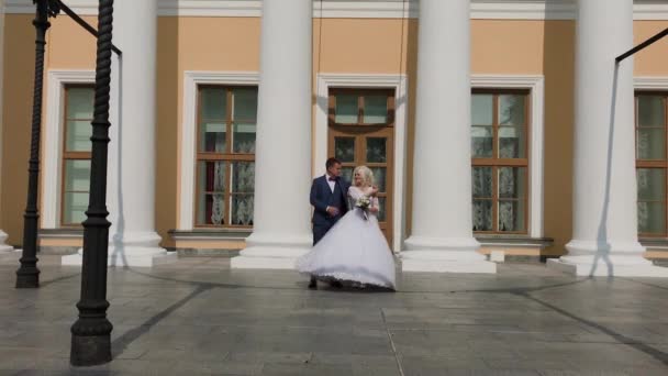 Glückliches Brautpaar tanzt an den Säulen im Park. — Stockvideo