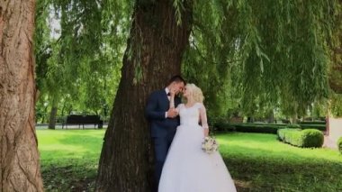 Mutlu yeni evliler parkta öpücük sarılmak.