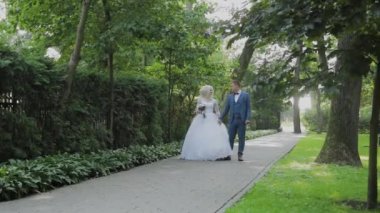 Mutlu yeni evliler parkta el tutarak yürümek, sarılmak öpücük.