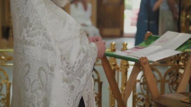 Yaşlı bir rahip sunakta durur ve bir dua okur..
