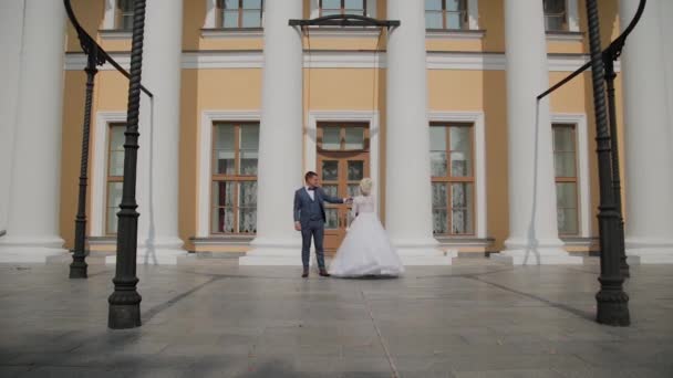 Lyckliga nygifta dansar sin dans på kolonnerna i parken. — Stockvideo