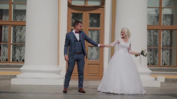 Felices recién casados bailan su danza en las columnas del parque . — Vídeo de stock