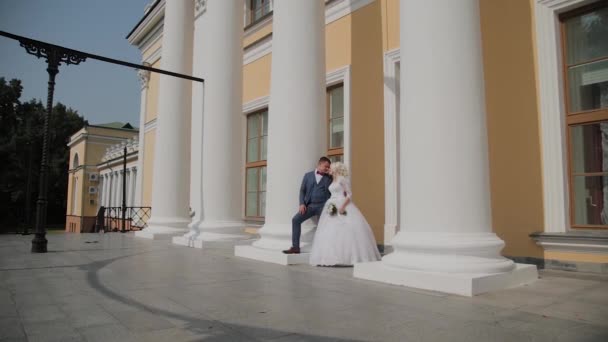 Os recém-casados felizes estão nas colunas do parque . — Vídeo de Stock