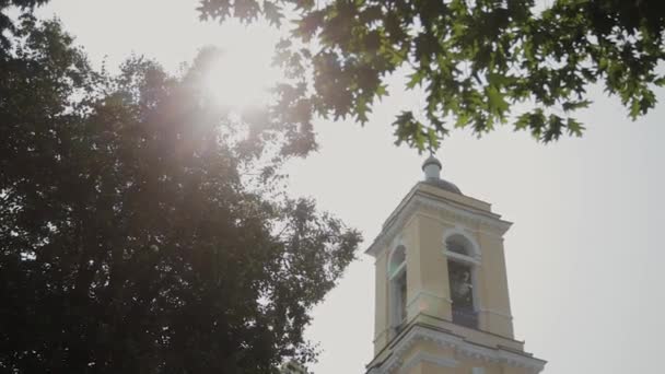 Güneşli bir günde ağaçların arasında güzel büyük kilise. — Stok video