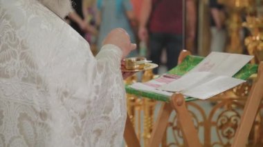 Yaşlı bir rahip sunakta durur ve bir dua okur..