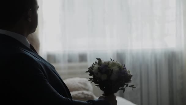 Young groom with a bouquet on the couch. — Stock Video