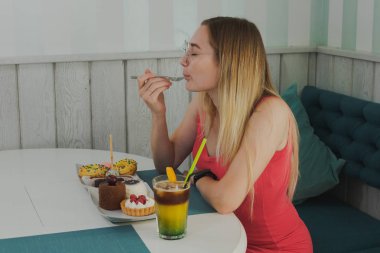 Bir kafede kız tatlı ve taze tatlılar yiyor.