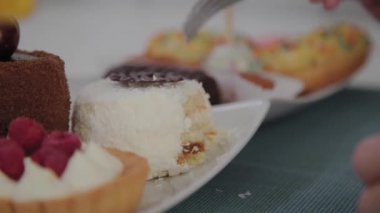 Güzel genç kız bir kafede bir masada oturur ve bir tabak tatlı taze tatlılar yiyor.