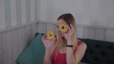Güzel kız bir kafede bir masada elinde donut ile poz.