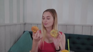Güzel kız bir kafede bir masada elinde donut ile poz.