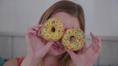 Güzel kız bir kafede bir masada elinde donut ile poz.
