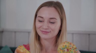 Güzel kız bir kafede bir masada elinde donut ile poz.