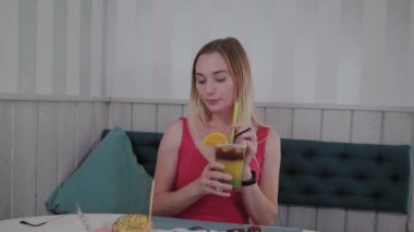 Güzel kız bir restoranda bir kokteyl içiyor.