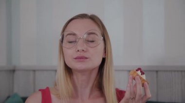 Güzel genç kız bir kafede bir masada oturur ve bir tabak tatlı taze tatlılar yiyor.