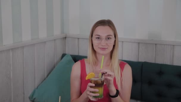 Vacker flicka dricker en cocktail i en restaurang. — Stockvideo