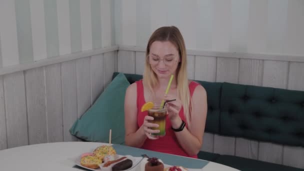 Красивая девушка пьет коктейль в ресторане . — стоковое видео