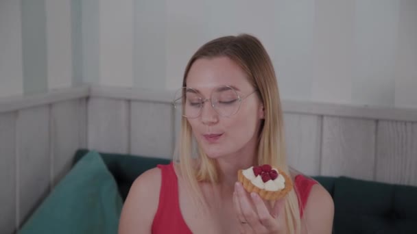 Menina bonita senta-se a uma mesa em um café e come doces sobremesas frescas de uma chapa . — Vídeo de Stock