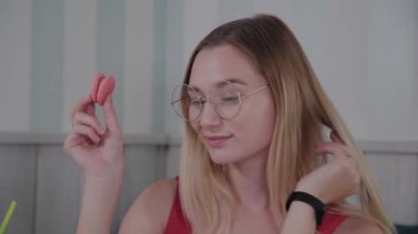 Güzel genç kız bir kafede bir masada oturur ve bir tabak tatlı taze tatlılar yiyor.