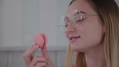 Güzel genç kız bir kafede bir masada oturur ve bir tabak tatlı taze tatlılar yiyor.