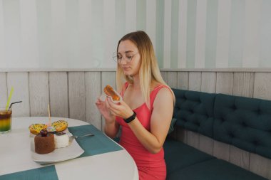 Bir kafede kız tatlı ve taze tatlılar yiyor.