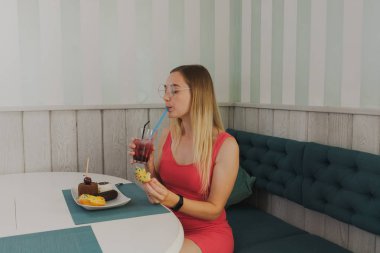 Bir kafede kız tatlı ve taze tatlılar yiyor.