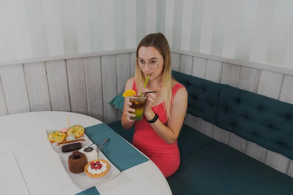 Девушка в кафе пьет сладкие десерты с напитком . — стоковое фото